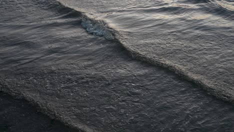 ocean waves calmly breaking with blue hour light on surface