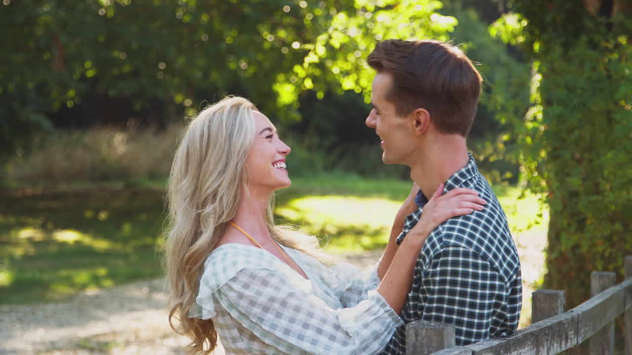 사랑하는 젊은 부부가 울타리  ⁇ 에 만나 시골에서 함께  ⁇ 고  ⁇ 안고 있습니다.