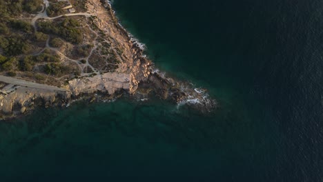 Aerial-drone-shot-over-waves-crashing-onto-rock