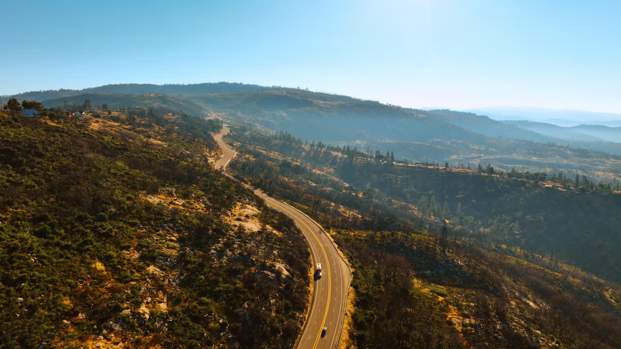 Flight over the highway in the mountains of Sierra National Forest, USA. Beautiful sunny scenery from top view.