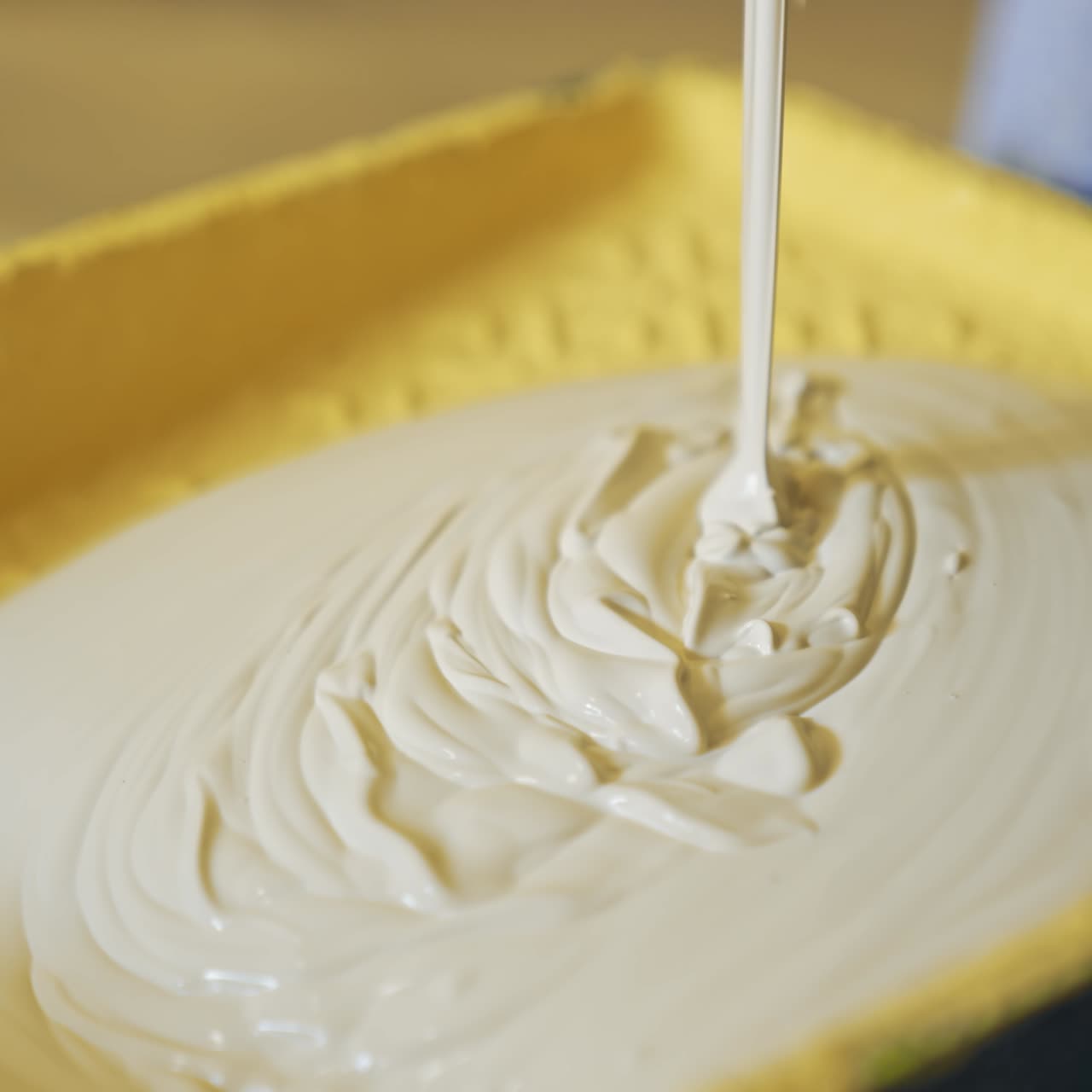 Light paint for home renovation. Worker pouring creamy color into a paint tray. Apartment decorating and home construction. Close-up