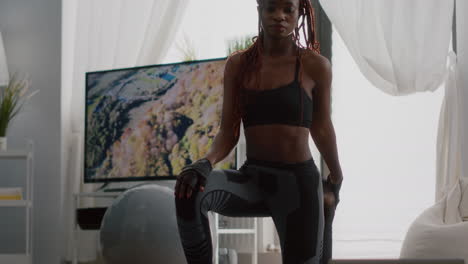 fitness woman with dark skin practicing yoga workout in living room