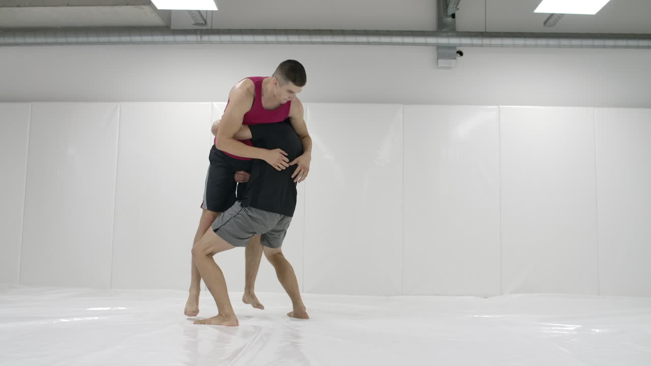 카메라는 남자 레슬링 선수들을 따라 이동합니다. mma 전투기들은 훈련 트랙에서 레슬링 장비를 작업합니다. 투구와 고통스러운 움직임을 포착합니다.