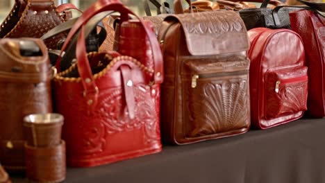 a large exhibition of genuine leather items in paraguay, handcrafted with brown and red leather, including wrapped thermoses. the leather is carved with patterns and figures