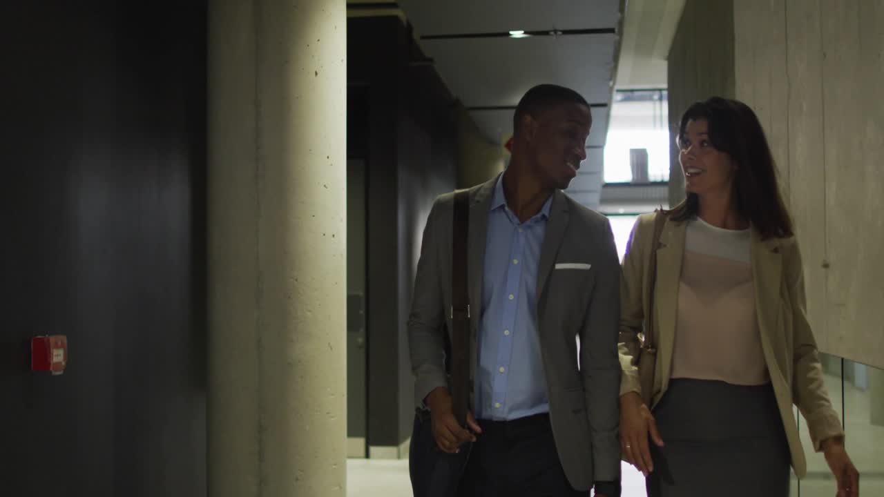Colleagues walking business corridor past restroom sign chatting as animated hearts growing fading
