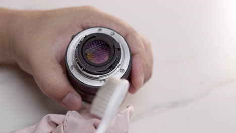 close up of hand cleaning camera ring with toothbrush and flannel cloth