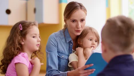 kids and teacher reading a book together in the preschool