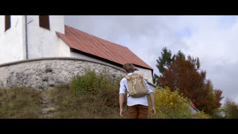 man hiking towards a church in autumn