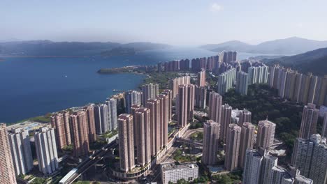 Hermosos-Rascacielos-De-Varios-Colores-Construidos-Uno-Al-Lado-Del-Otro-Entre-La-Naturaleza-Verde-Y-El-Mar-Azul-En-Hongkong