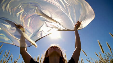 woman holding scarf in a field on a sunny day