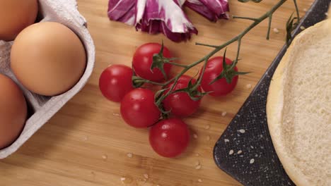 zoom out of fresh tomatoes and various ingredients while cooking a tasty organic hamburger detail medium shot