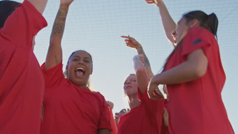 portrait of excited womens soccer team celebrating winning game shot from low angle