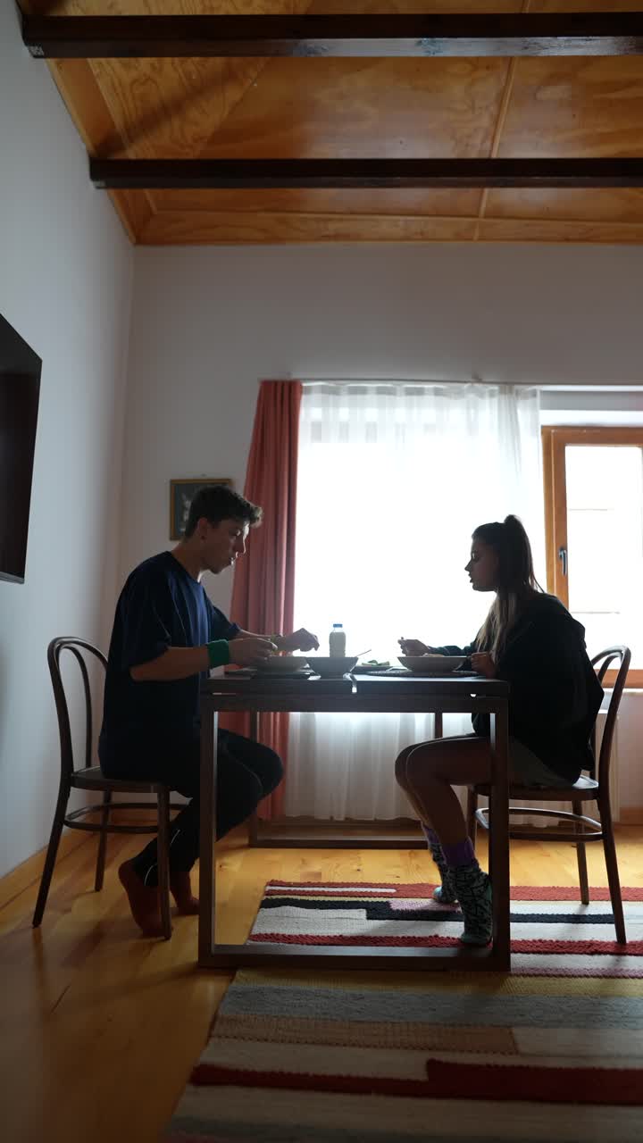 Couple eating together at a wooden table in a room