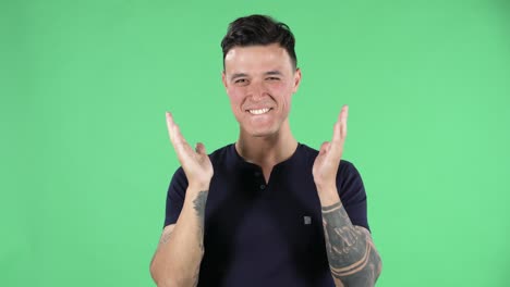 retrato de un joven guapo mira a la cámara con emoción, luego suspira de alivio y sonríe, recibe información agradable. pantalla verde