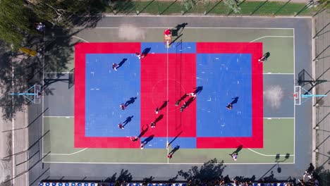 top down aerial view of teams playing volleyball on outdoor court in city park on sunny day