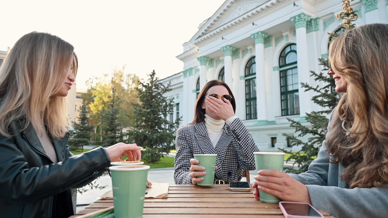 Three women talking and drinking coffee at a terrace
