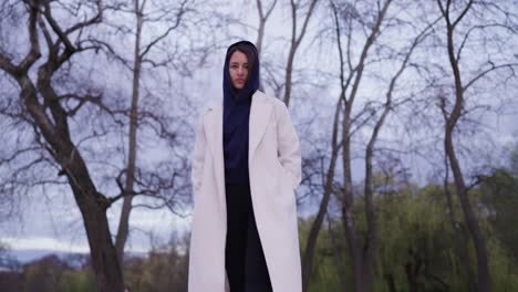 low angle view of serious woman wearing hoodie and long coat walk by