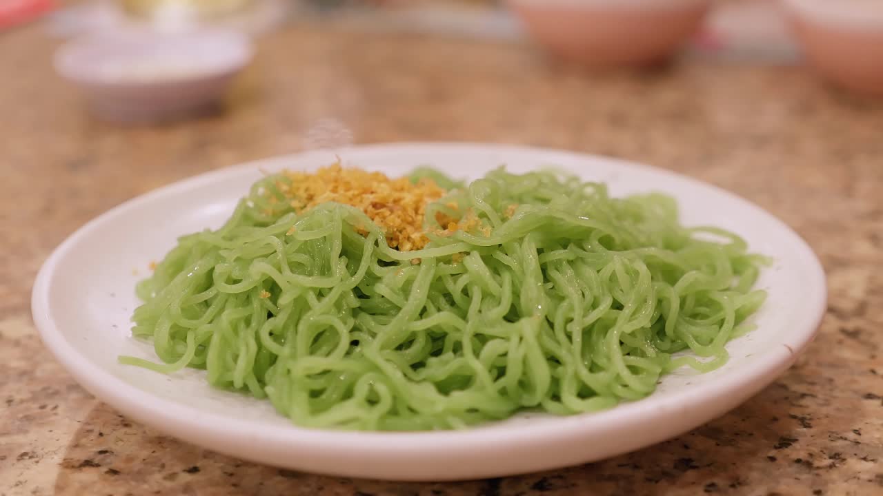 detalle del plato con pasta verde y condimentos