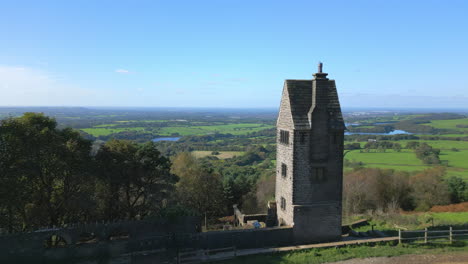 lone stone tower building on hilltop, flight towards and past revealing countryside beyond