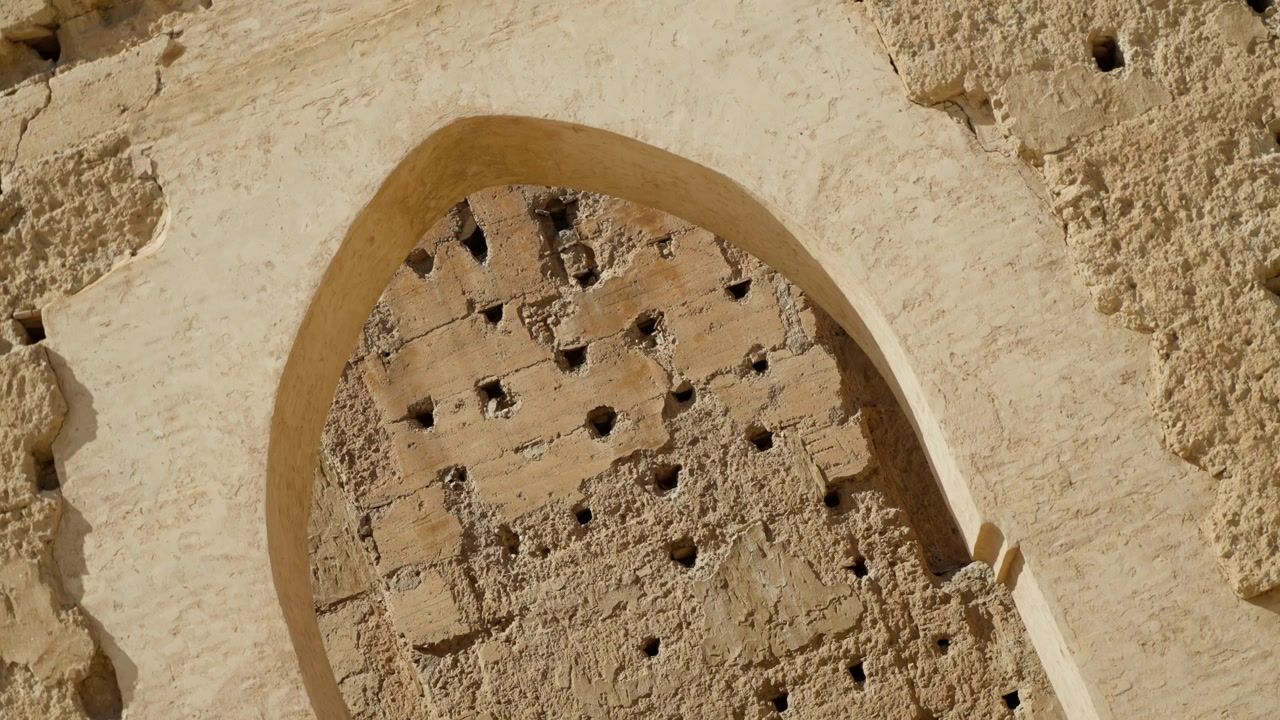 Primo piano di un arco in pietra consumato dal tempo con parete texturizzata a Marrakech, Marocco.