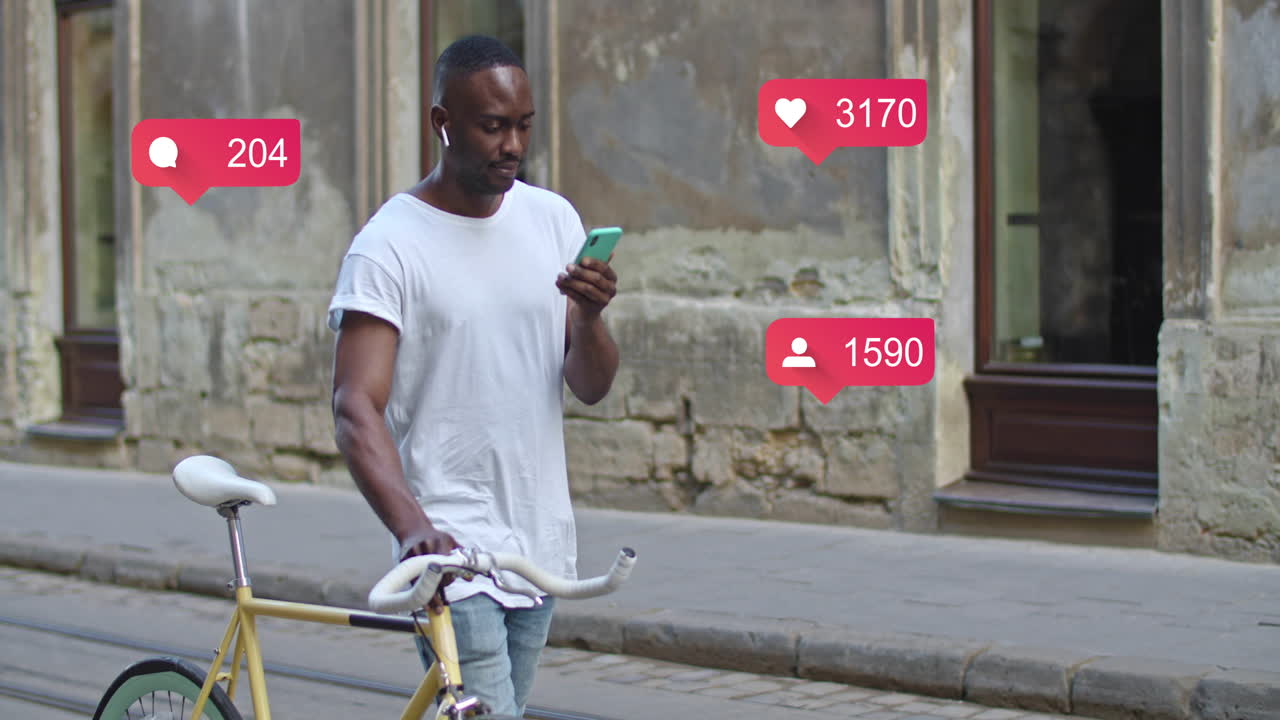 A man walks with his bicycle while checking social media notifications on his smartphone in an urban environment
