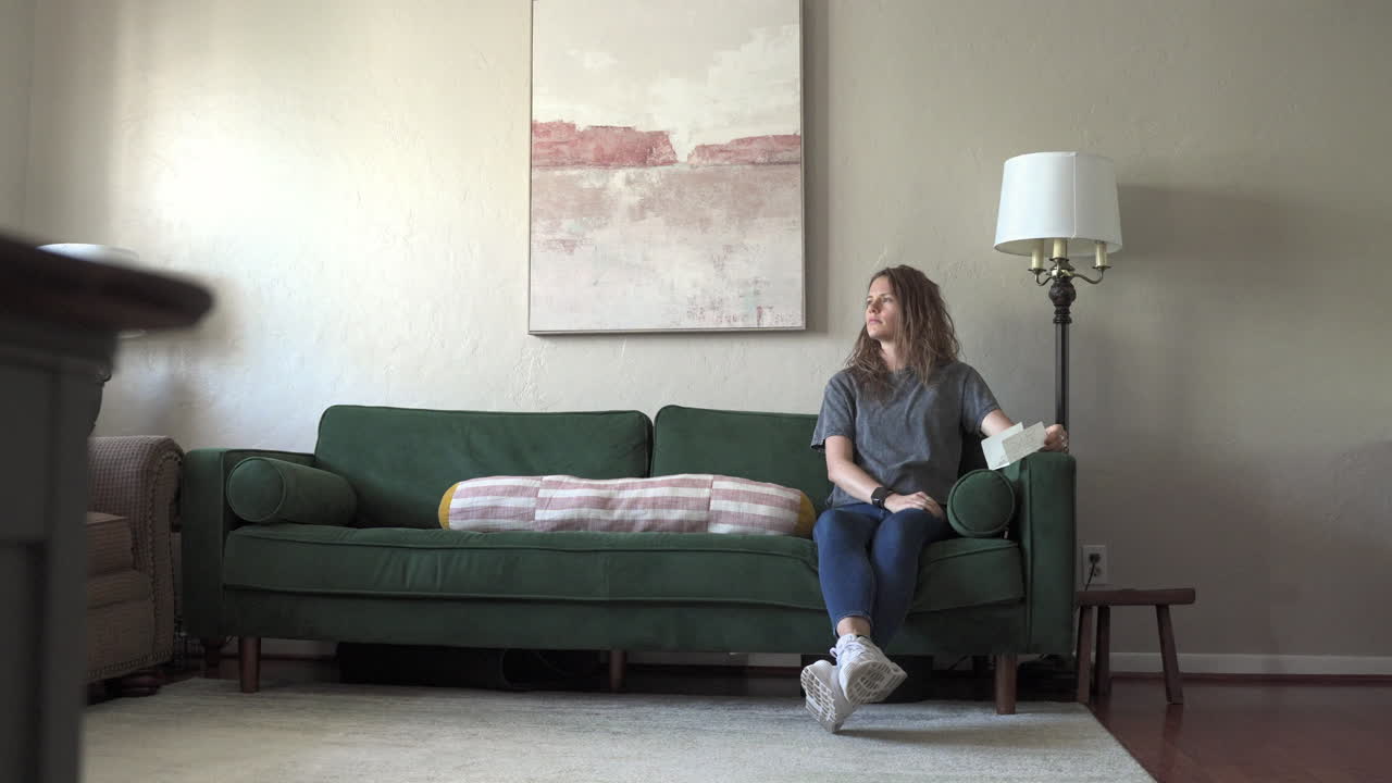 A wide shot features a woman looking sad and stoically into the distance. The camera slowly slides from left to right, emphasizing her emotional state and the surrounding atmosphere.