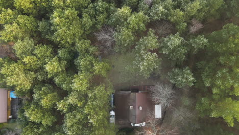 drone truck shot from above the green forest on a house between the trees in bartoszylas, poland on a cloudy day