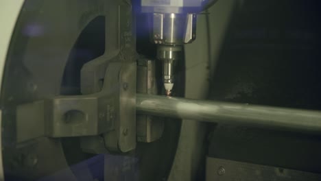 imágenes en cámara lenta de una máquina de corte por láser que hace agujeros y marcas en una tubería de acero