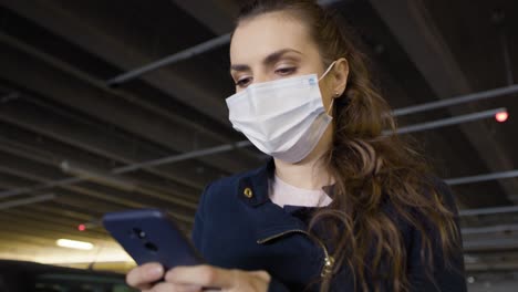 Bottom-view-of-woman-in-mask-walking-with-mobile-phone