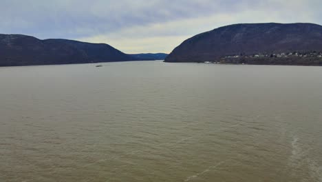 A-drone-point-of-view-flying-over-a-vast-river-valley-with-mountains-that-have-a-light-dusting-of-snow