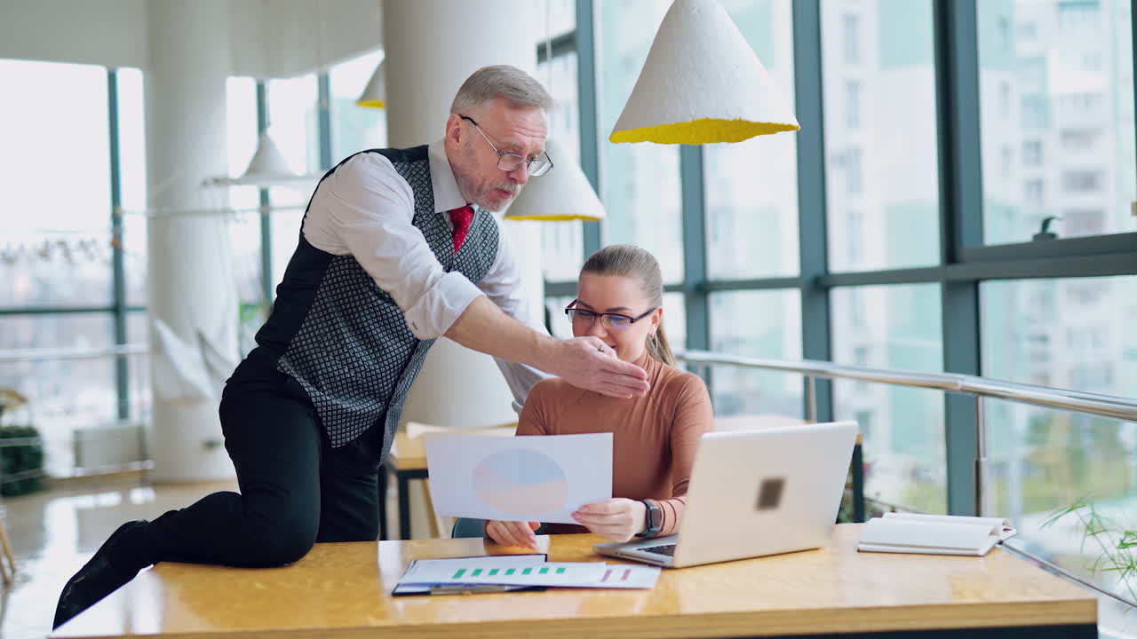 Voksen entreprenør og sekretær i det moderne selskapet. Ung kvinne med briller snakker med sjefen sin og smiler.