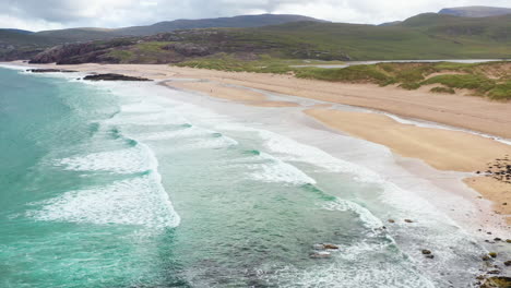 cinematic tilting up drone shot of waves on sanwood bay beach in sutherland scotland and north atlantic ocean waves