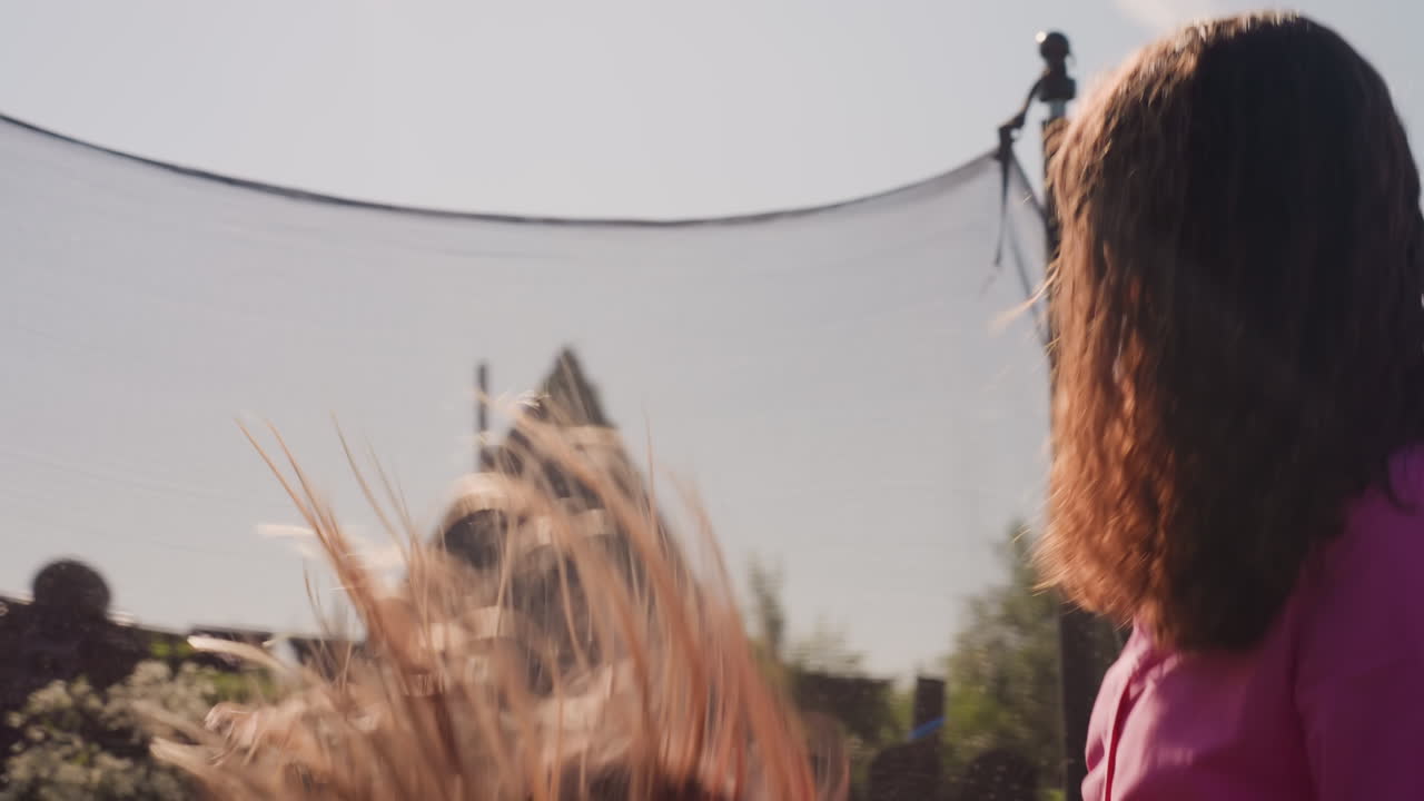 Joyful Trampoline Play, Child And Caregiver Bounce Happily Outdoors, Sunlit Backyard With Joyful Child And Adult Bounce, Golden Evening Light Illuminates Child Spinning With Caring Adult Outside