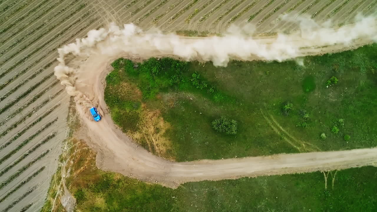 vista aérea de un coche azul corriendo en una pista de tierra