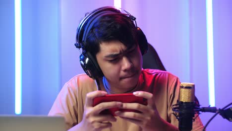 asian man playing video game with mobile phone then lose the game while live stream