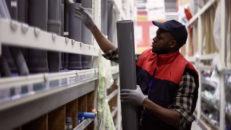 salesman standing in household hypermarket, arranging products - tubes, pipes