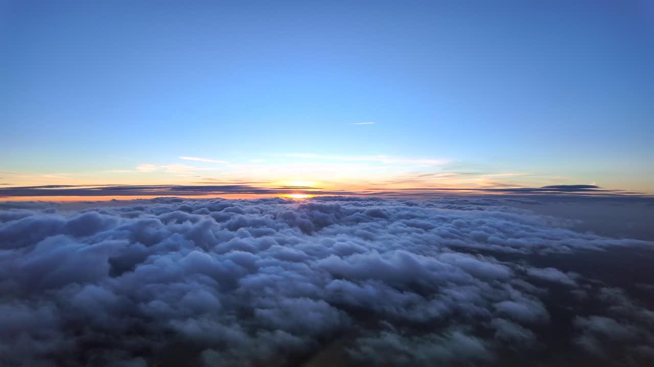 Immersive hyperlapse taken from. an airplane cockpit while flying at sunset over some stratus ckouds an a sun sinking in a golden horizon illuminating the clouds with pastel colors