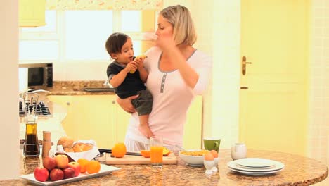 Mother-busy-in-kitchen-holding-baby-while-father-late-for-work