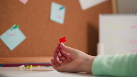 child spins pin with red flag in hand against cork board