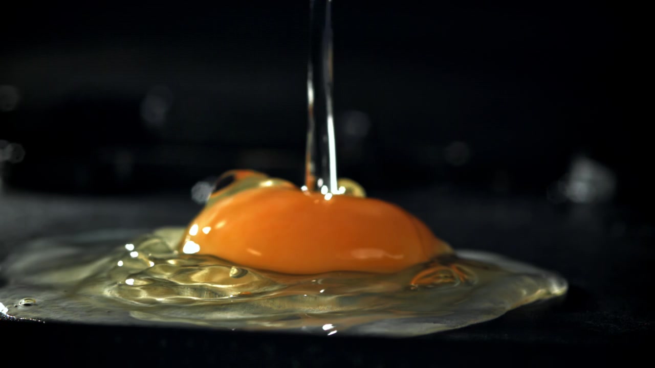 Slow Motion of Raw Egg Yolk and White Dropping on Dark Surface