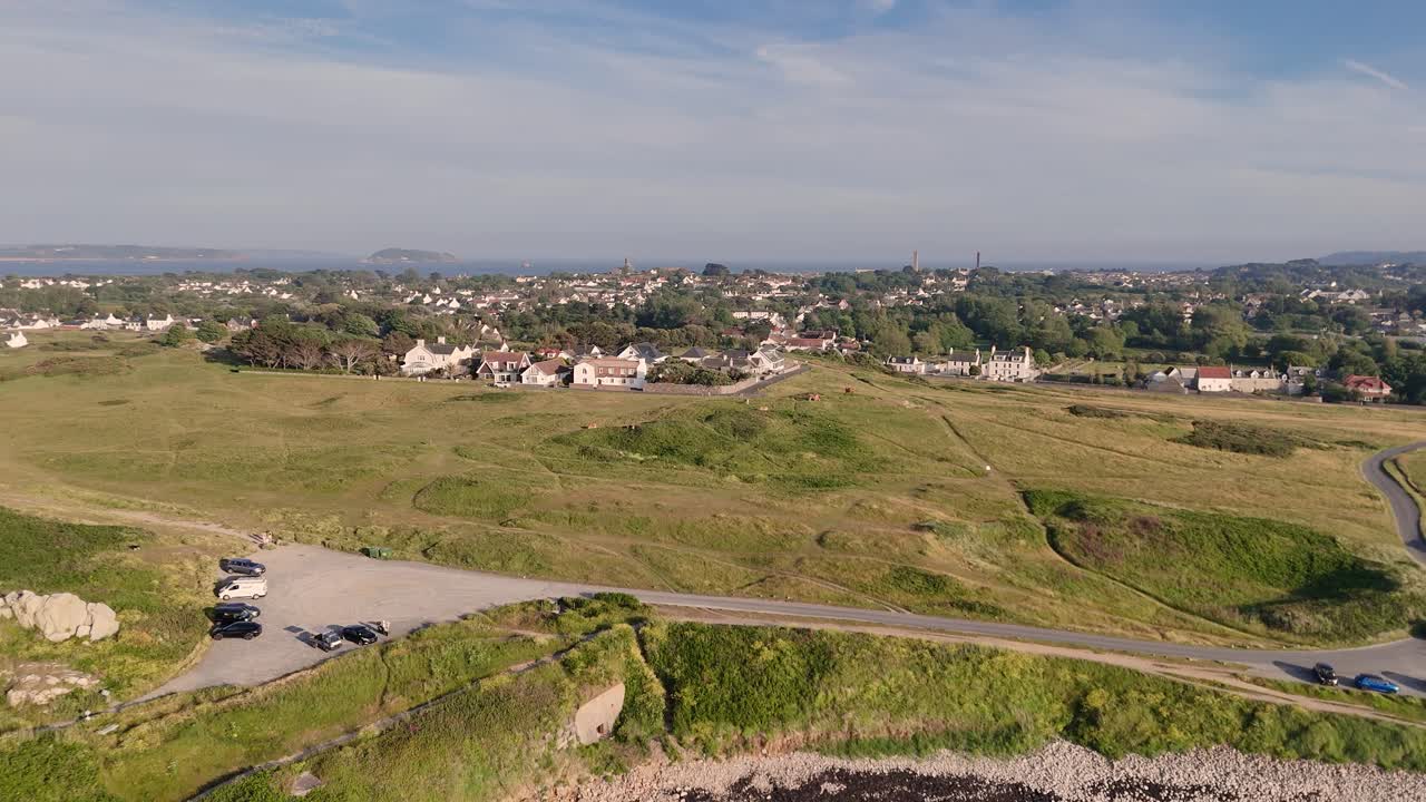 Guernsey.Drone footage of coast road alongside heathland and golf course Lancresse north of Guernsey on bright sunny day with views across to Islands in the distance
