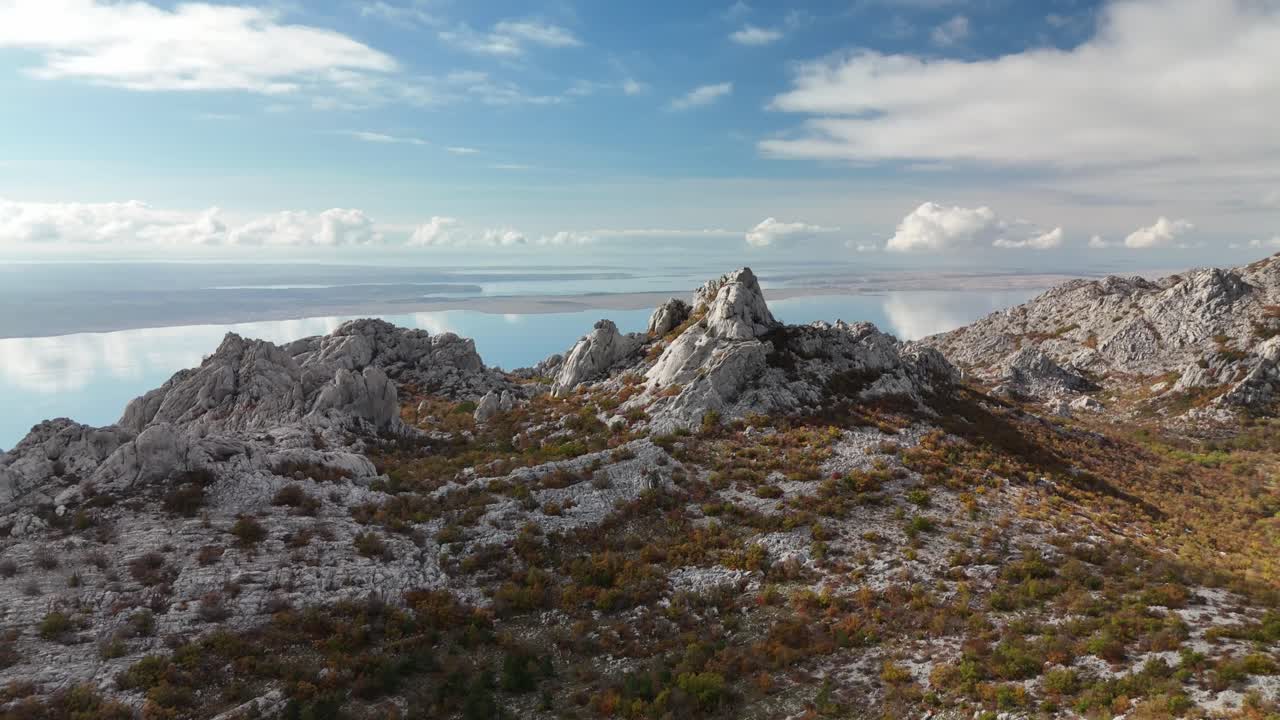 Drone turn over the rugged Velebit mountain peaks near Starigrad Paklenica, the shimmering Adriatic Sea beyond. Filmed on a stunning sunny Autumn day