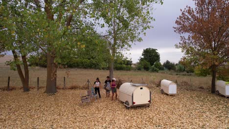 nomad family resting in countryside near small trailers