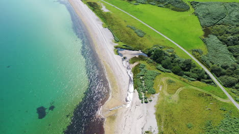 aerial shot looking down on the beautiful beach on the island of islay, calm blue sea and bright sunshine