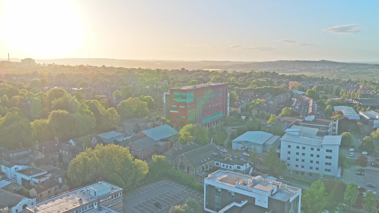 Barnsley town centre in South Yorkshire, England, revealing modern office buildings, suburban neighborhoods, and golden hour landscape, drone ascent aerial shot.
