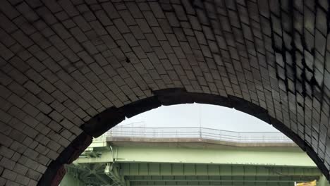 under brickwork tiled stone industrial archway view of arched steel girder railway bridge crossing