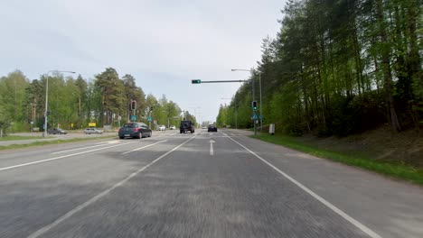 driving through the intersection of a rural street flanked by a forest during a sunny morning