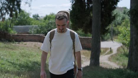 young man walking with guitar on street near forest