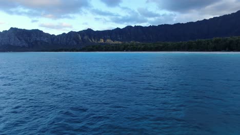 an offshore view of the ocean, forest, and mountains of oahu