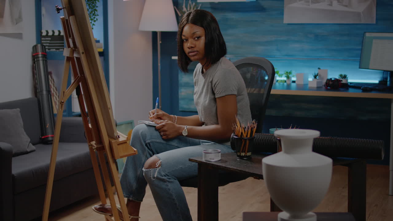 African american woman drawing vase on canvas in art studio